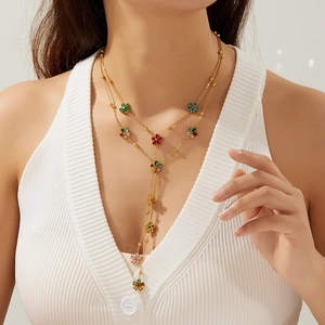 Collier élégant doré en Y avec pampilles de fleurs en cristal coloré porté par un mannequin