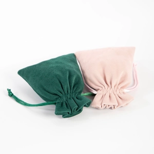 Close-up of velvet drawstring pouches in dark green and light pink for jewelry storage