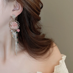 Detail of pink crystal flower earrings with long rhinestone tassels on a model