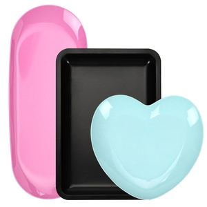 Set of colorful stainless steel trays in rectangular, oval, and heart shapes on white