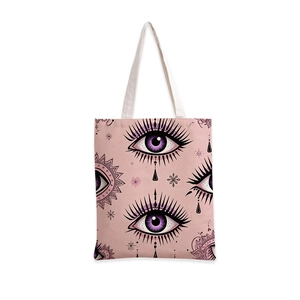 Détail du sac cabas en toile rose avec motifs géométriques d'yeux violets et mandala