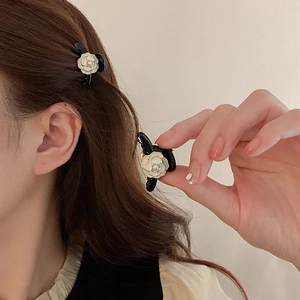 Close-up of a mini black hair claw with a white 3D camellia flower and pearl detail
