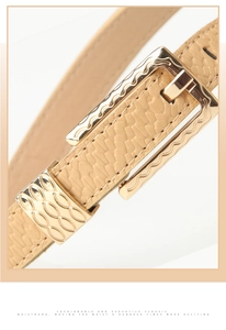 Close-up of beige snakeskin texture belt with engraved gold buckle for women