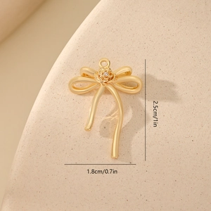 Macro detail of gold bow charm with center flower and rhinestone, 2.5cm size reference