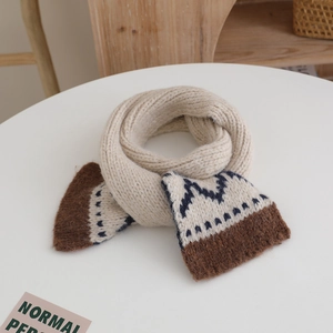 Detail of a beige knit scarf featuring brown and navy blue geometric patterns