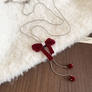 Close-up of burgundy velvet bow necklace with zircon pendant on soft textured fabric