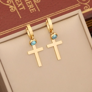 Golden cross and turquoise earrings on a minimalist jewelry box with vintage props