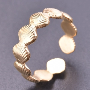 Macro shot of gold adjustable open ring featuring unique seashell texture and wave design