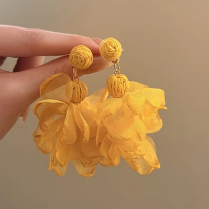 Detail of yellow raffia and chiffon flower drop earrings for vacation style