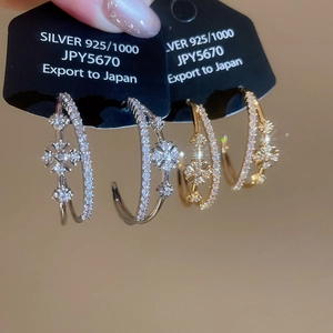 Gros plan de boucles d'oreilles double couche en C dorées avec fleurs en zircones