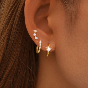 Macro shot of s925 silver gold earring set with white zircons worn on ear