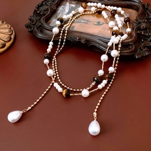 Detail of vintage necklace featuring pearls, tiger eye beads and gold metallic chain