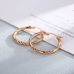 Dettaglio di orecchini a cerchio intrecciati in oro rosa con trama a spirale elegante