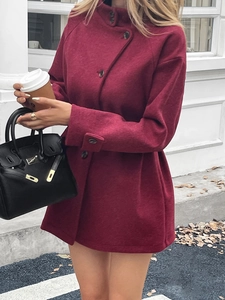 Close-up of a red wool mid-length coat on a model in a European street setting