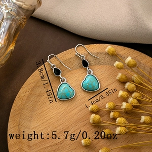 Close-up of heart turquoise earrings with size measurements on a rustic wooden tray