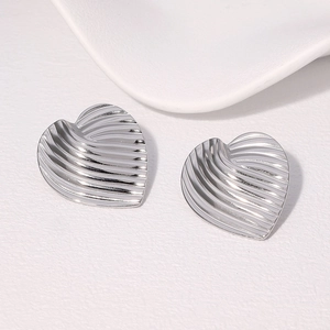 Macro detail of silver heart earrings with textured vertical ridges and metallic finish