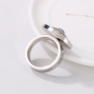 Detail shot of a silver zircon ring resting on a white porcelain dish with sharp focus
