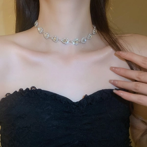 Close-up of sparkling silver heart-shaped diamond necklace set on woman's collarbone