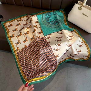 Silk-feel square scarf with horse print and green border styled on a white handbag