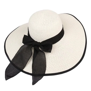 Beige wide-brim straw sun hat with black ribbon bow and textured woven pattern for summer