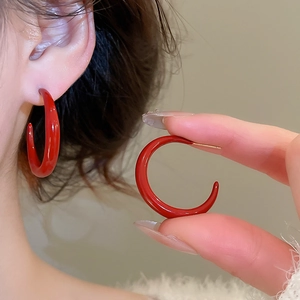 Close-up of elegant red enamel C-shaped hoop earrings worn by a model in vintage style