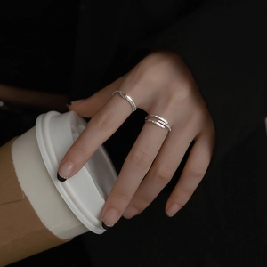 Detail of silver wavy band and multi-layer zircon paved cross ring worn by a model