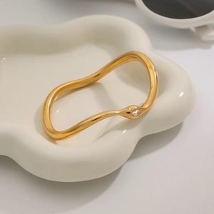 Detail of gold snake bracelet featuring sparkling stone setting and metallic finish