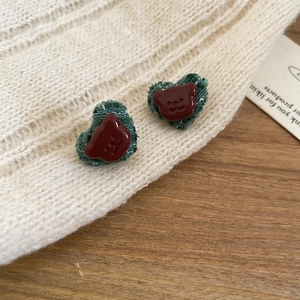 Detail view of heart-shaped corduroy earring featuring a 3D resin bear on fabric