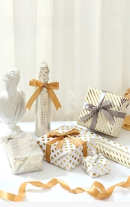 Detail of gold foil striped gift wrap paper with silk ribbons and modern patterns