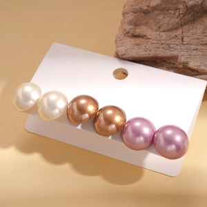 Detail shot of a six-piece faux pearl earring set with lustrous creamy white and purple tones