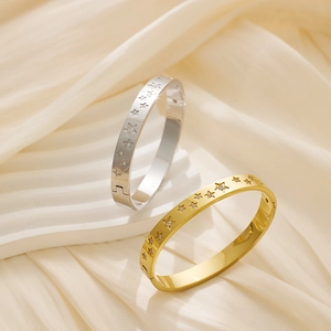 Detailed view of gold and silver star-patterned bangles on soft cream velvet fabric