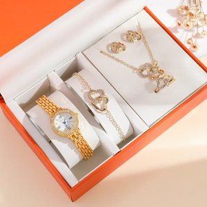 Macro view of gold quartz watch set with rhinestone heart jewelry in an orange gift box