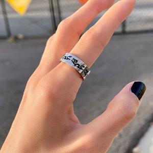 Close-up of a silver titanium steel wide band ring with black Chinese dragon pattern