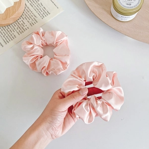 Detailed close-up of premium pink satin floral scrunchies with elegant glossy texture