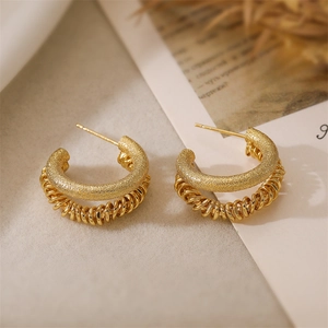 Detail of double-layer gold hoop earrings with matte and twisted spiral textures