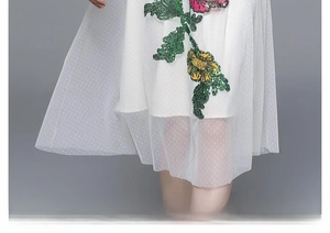 Détail d'une robe trapèze blanche avec voile en tulle et broderies de fleurs à paillettes