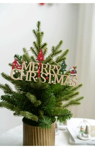 Detail of wooden Merry Christmas sign on a potted pine tree with Santa Claus motif