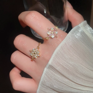 Detailaufnahme der Goldblumenringe mit rosa Zirkonia und verstellbaren Gliederkettenbändern