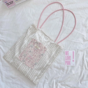 Close-up of white lace tote bag featuring pink vintage patchwork and round rope handles