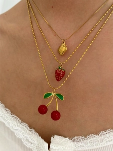 Detaillierte Schicht-Halskette mit goldener Erdbeere und roten Kirschanhängern am Model