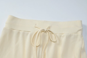 Detail of cream ribbed knit trousers showing elastic waistband with drawstring closure