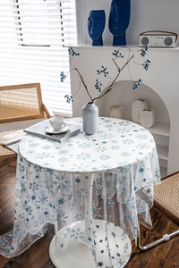 Close-up of white mesh tablecloth with blue snowflakes and stars on a round table