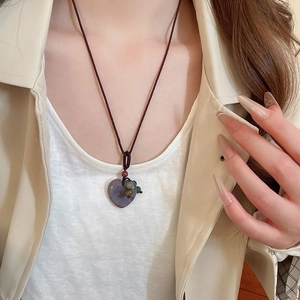 Detail of woven rope necklace with heart-shaped purple and green natural stone pendant