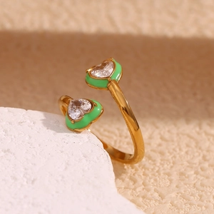 Detailed macro of a gold-plated ring featuring green enamel hearts and inset zircons