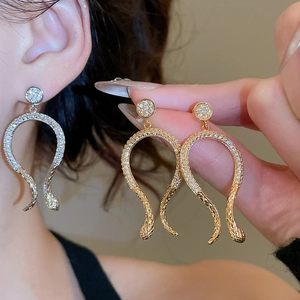 Macro detail of 14k gold plated snake earrings with shimmering pavé zircon stones
