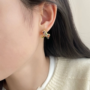 Golden horse earrings set with colorful zircon crystals shown on model's ear
