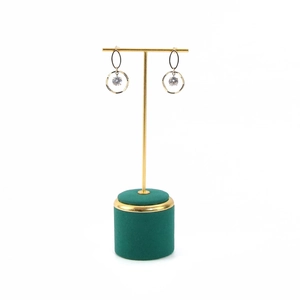 Detail of gold circular earrings with clear zircon on a luxury green velvet T-bar stand