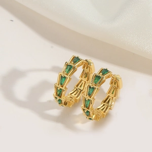 Detail of gold-plated hoop earrings with green triangle zircons and scale texture