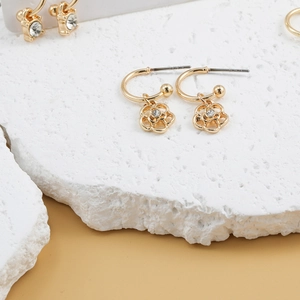 Detail of golden flower earrings with sparkling faux gemstone centers on stone