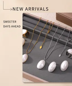 Close-up of gold and silver oval mother-of-pearl jewelry set on a grey velvet tray
